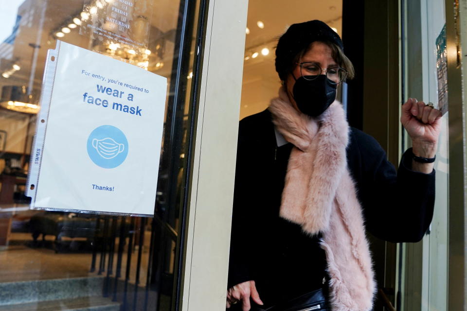 Une personne portant un masque sort d'un magasin devant un 