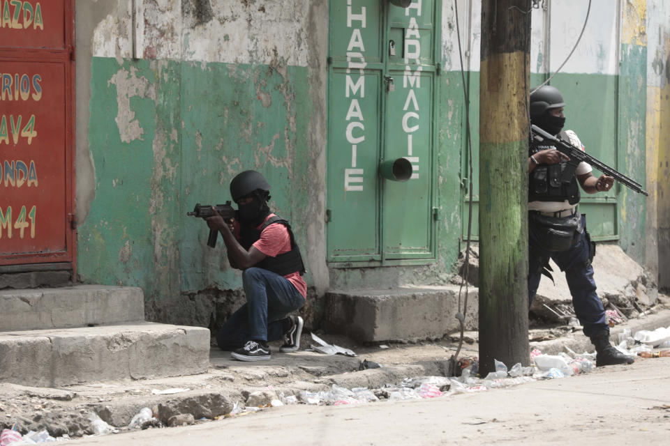 Police officers take cover during an anti-gang operation in the Portail neighborhood of Port-au-Prince, Haiti, Tuesday, April 25, 2023, a day after a mob in the Haitian capital pulled 13 suspected gang members from police custody at a traffic stop and beat and burned them to death with gasoline-soaked tires. (AP Photo/Odelyn Joseph)