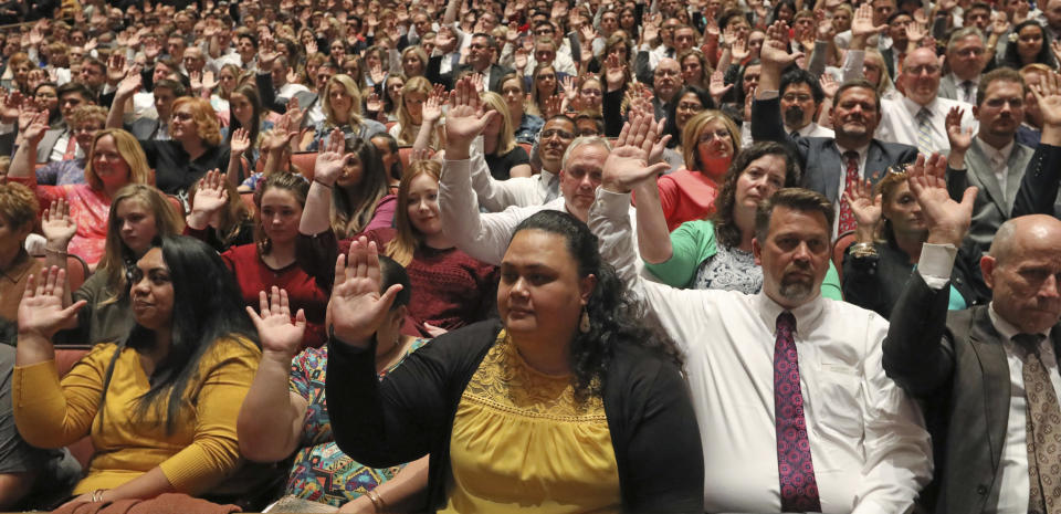 Mormons participate in a long-standing custom called a "sustaining" when Latter-day Saints stand and raise their hands during the twice-annual conference of The Church of Jesus Christ of Latter-day Saints, Saturday, Oct. 6, 2018, in Salt Lake City. (AP Photo/Rick Bowmer)