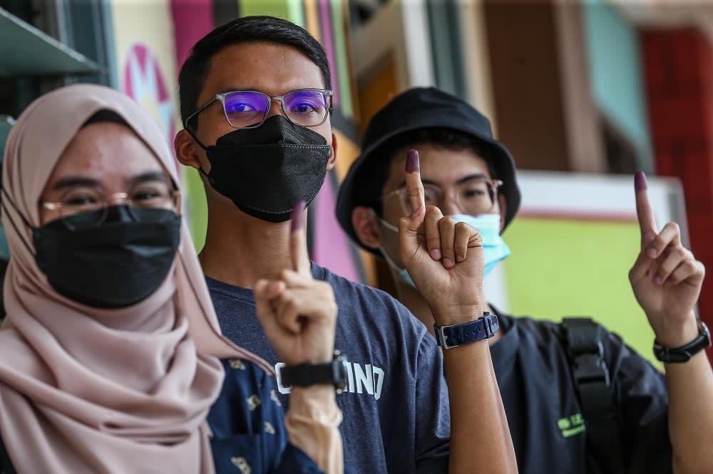 First-time voters Syazwani Rafaeh Shukor, 19 (left), Mohd Khairul Azhar Mohd Ridza, 18, (centre) and Jonathan Chua Ming Jun, 19 (right) at the SK Ismail 1 polling centre to cast their votes, March 12, 2022. ― Pictures by Hari Anggara