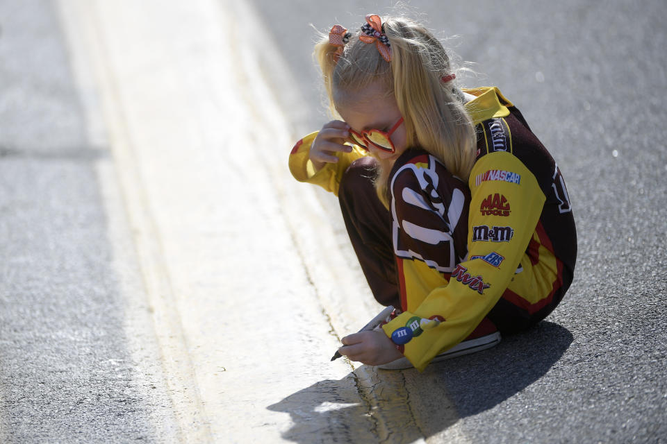 Four-year-old Clover Grant, of Jacksonville, Fla., writes her name on the track before the NASCAR Daytona 500 auto race at Daytona International Speedway, Monday, Feb. 17, 2020, in Daytona Beach, Fla. (AP Photo/Phelan M. Ebenhack)