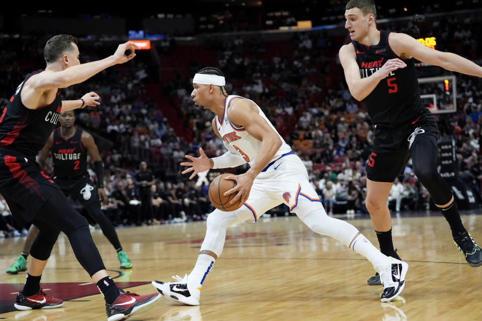 New York Knicks guard Josh Hart, center, drives to the basket as Miami Heat forward Duncan Robinson, left, and forward Nikola Jovic (5) defend during the first half of an NBA basketball game, Tuesday, April 2, 2024, in Miami. (AP Photo/Lynne Sladky)