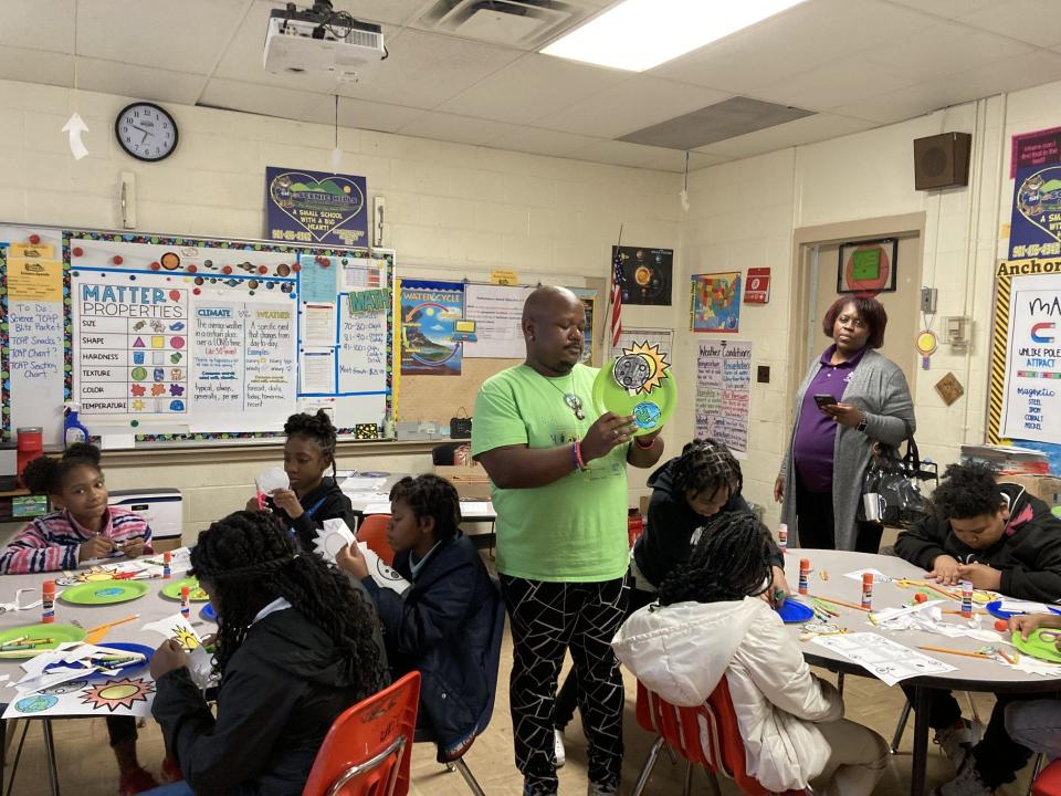 Kael Moore, a science teacher at Scenic Hills Elementary, shows his students what their art project should look like when completed.