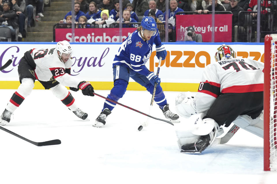 Toronto Maple Leafs' William Nylander (88) shoots on Ottawa Senators goaltender Joonas Korpisalo, right, as Senators' Travis Hamonic (23) closes in during the second period of an NHL hockey match in Toronto, on Wednesday, Nov. 8, 2023. (Chris Young/The Canadian Press via AP)