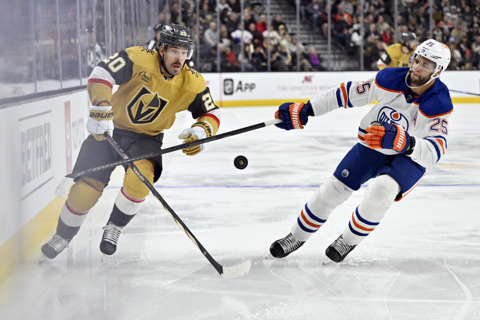 Vegas Golden Knights center Chandler Stephenson (20) and Edmonton Oilers defenseman Darnell Nurse (25) chase the puck during the second period of an NHL hockey game Tuesday, Feb. 6, 2024, in Las Vegas. (AP Photo/David Becker)