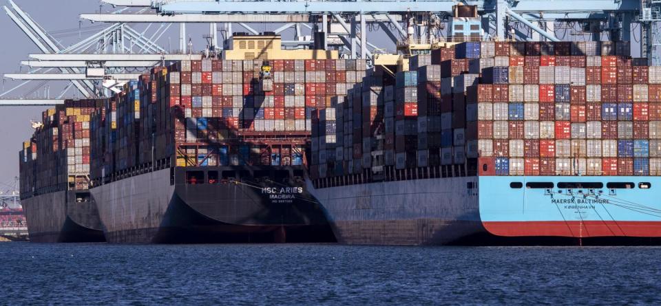 Three container ships are docked at a port.