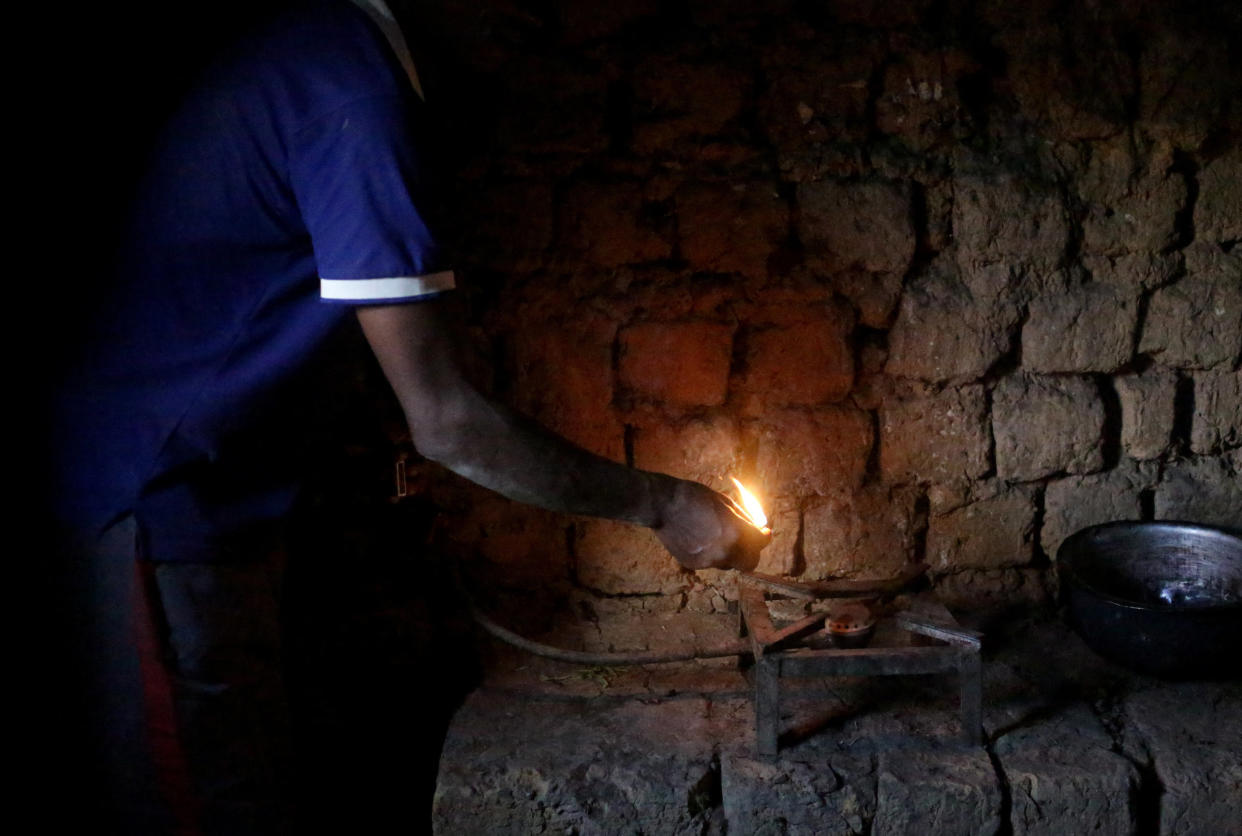 Etiene Twagirayezu, 60, lights his biogas digester in his home on November 18, 2017 in Rutabo, Rwanda. Twagirayezu says that before his digester, he'd spend up to 3 hours a day gathering 10 kilograms of wood, and saw kids get injured climbing trees and be late to school doing the same. He added he was happy his workload at home was reduced due to being able to use his cow's and pig's poo instead of wood as fuel, as well as about the resulting decrease of deforestation. (Photograph by Yana Paskova)