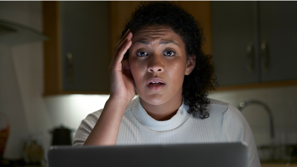 Shocked woman on computer who has just been scammed. 