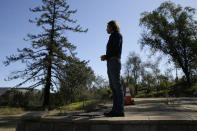 In this Tuesday, Feb. 25, 2020, photo, Jason Meek, whose Northern California wine country home was destroyed in 2017, stands in the driveway and looks out at the remains of his home in Santa Rosa, Calif. A $13.5 billion settlement between victims, including Meek, of California's catastrophic wildfires and Pacific Gas & Electric was supposed to bring some peace and hope to people still reeling from the devastation. Instead, it has sparked confusion, resentment, suspicion and despair as the victims, government agencies, and lawyers grapple for their piece of the settlement fund. (AP Photo/Eric Risberg)