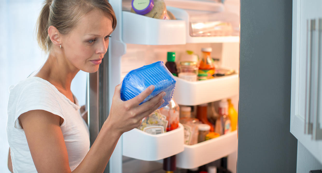 Woman holding pack of food from fridge to check use-by date. (Getty Images)