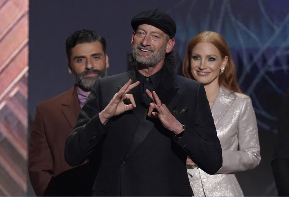 Troy Kotsur accepts the award for outstanding performance by a male actor in a supporting role for "CODA" at the 28th annual Screen Actors Guild Awards at the Barker Hangar on Sunday, Feb. 27, 2022, in Santa Monica, Calif. Oscar Isaac, left, and Jessica Chastain look on from behind. (AP Photo/Chris Pizzello)