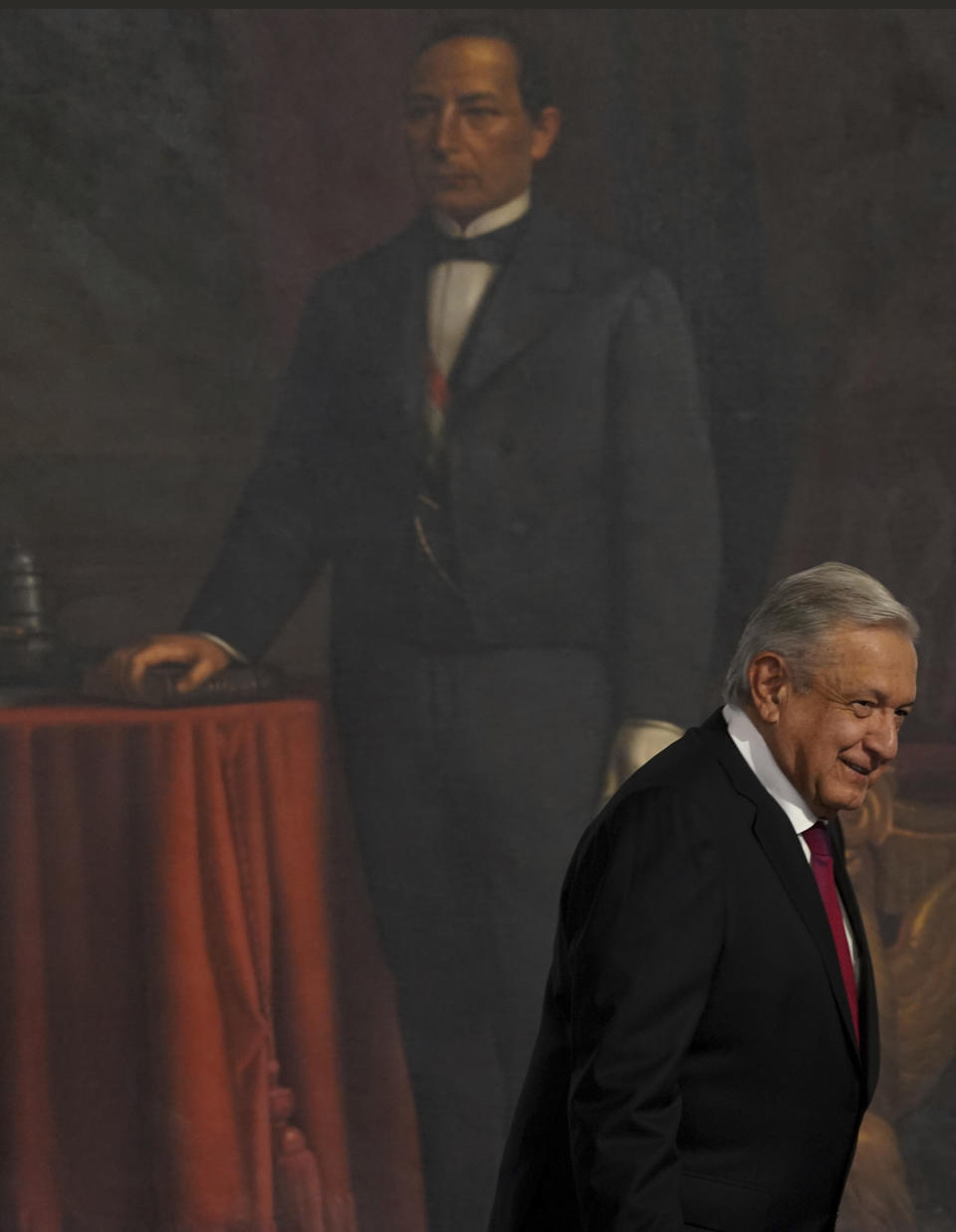 Backdropped by a portrait of Mexico's 26th president Benito Juarez, Mexican President Andres Manuel Lopez Obrador smiles as he arrives to deliver his third state of the nation address, at the National Palace in Mexico City, Wednesday, Sept. 1, 2021. (AP Photo/Fernando Llano)