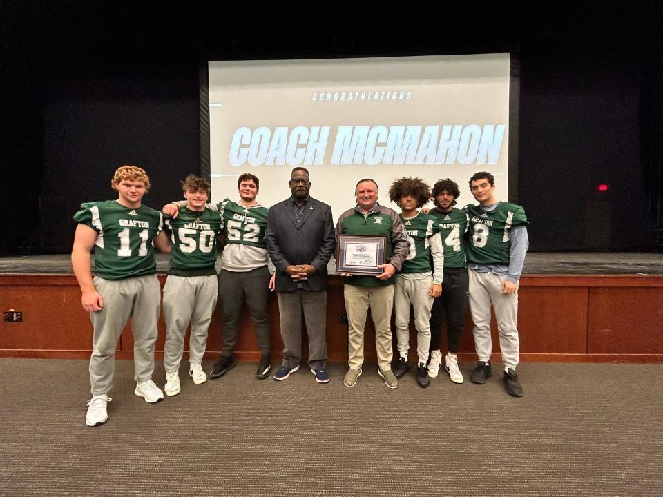 Grafton football captains and New England Patriots legend Andre Tippett surround coach Chris McMahon after the Patriots honored McMahon as their Coach of the Week.