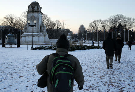 Commuters make their way towards the U.S. Capitol from Union Station on a chilly morning after a light snow fell in Washington January 21, 2016. REUTERS/Jonathan Ernst