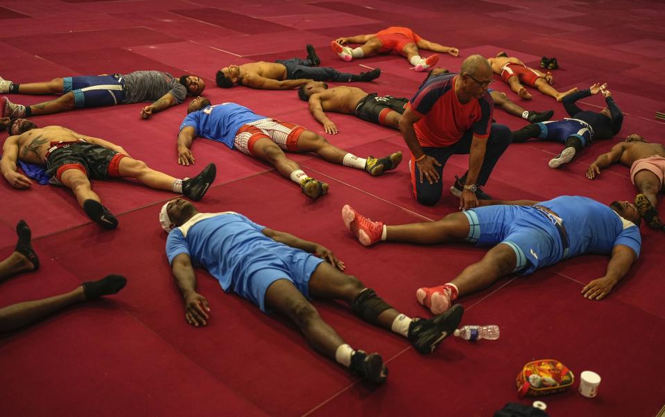 Miembros del equipo nacional de lucha grecorromana de Cuba estiran sobre colchonetas durante una sesión de entrenamiento preolímpico en Varadero, Cuba, el 3 de abril de 2024. (AP Foto/Ramón Espinosa)