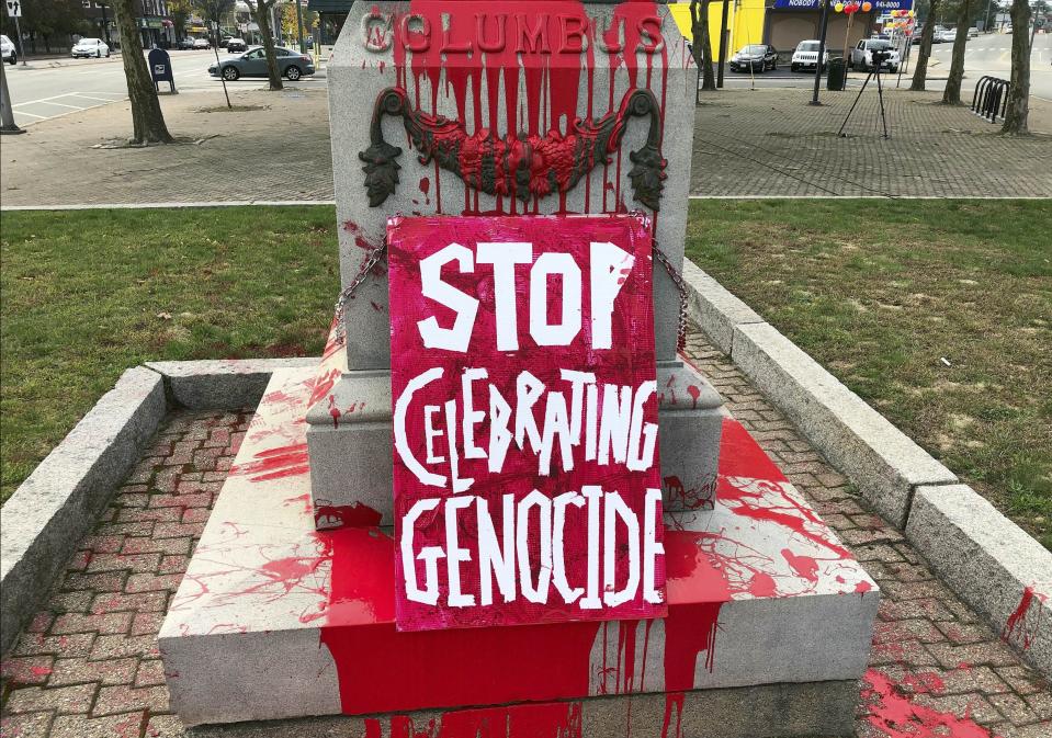 A sign reading "stop celebrating genocide" sits at the base of a statue of Christopher Columbus on Monday, Oct. 14, 2019, in Providence, R.I., after it was vandalized with red paint on the day named to honor him as one of the first Europeans to reach the New World. The statue has been the target of vandals on Columbus Day in the past. (AP Photo/Michelle R. Smith)