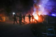 Ukrainian riot police run to push protesters, who planned to stop buses carrying passengers evacuated from the Chinese city of Wuhan, outside Novi Sarzhany, Ukraine, Thursday, Feb. 20, 2020. Several hundred residents in Ukraine's Poltava region protested to stop officials from quarantining the evacuees in their village because they feared becoming infected. Demonstrators put up road blocks and burned tires, while Ukrainian media reported that there were clashes with police, and more than 10 people were detained. (AP Photo/Efrem Lukatsky)