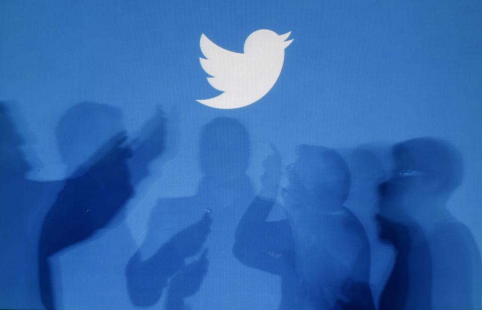 The shadows of people holding mobile phones are cast onto a backdrop projected with the Twitter logo in this illustration picture taken in Warsaw September 27, 2013. REUTERS/Kacper Pempel