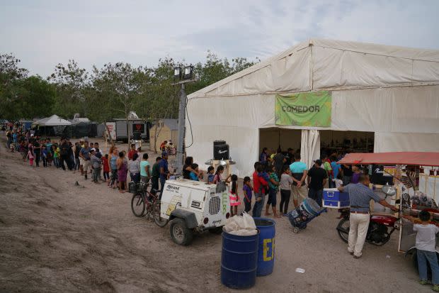 People wait in line for a meal at the Matamoros migrant encampment.