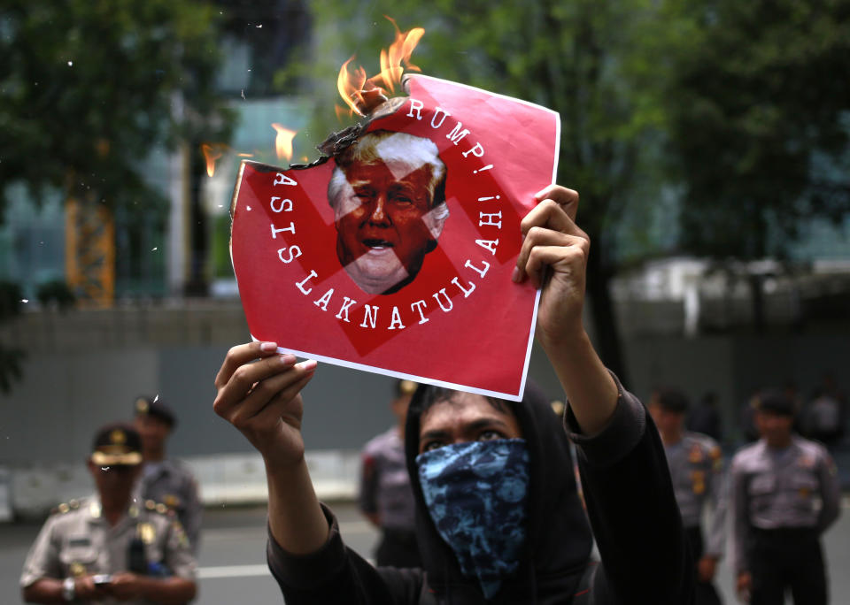 An activist burns a poster depicting U.S. President Donald Trump during a protest outside the U.S. Embassy in Jakarta, Indonesia, Saturday, Feb. 4, 2017. Dozens of students and activists from several rights groups staged the protest calling on the Indonesian government and the international community to help stop Trump's order that temporarily banned travelers from seven predominantly Muslim countries. (AP Photo/Dita Alangkara)