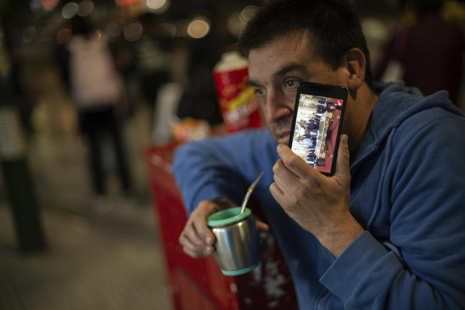 Un hombre toma mate mientras escucha el mensaje del presidente Javier Milei anunciando nuevas medidas económicas, el miércoles 20 de diciembre de 2023, en Buenos Aires, Argentina. (AP Foto/Mario De Fina)