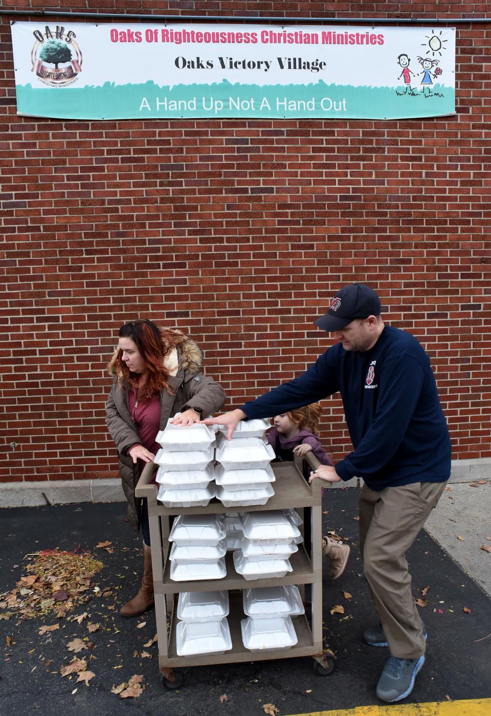 Firefighter/paramedic Chad Hudson with the help of his wife Mindy Hudson and daughter Josie, 6, wheel out the Thanksgiving dinners to handout at Oaks Village in Monroe Wednesday, November 24, 2021.