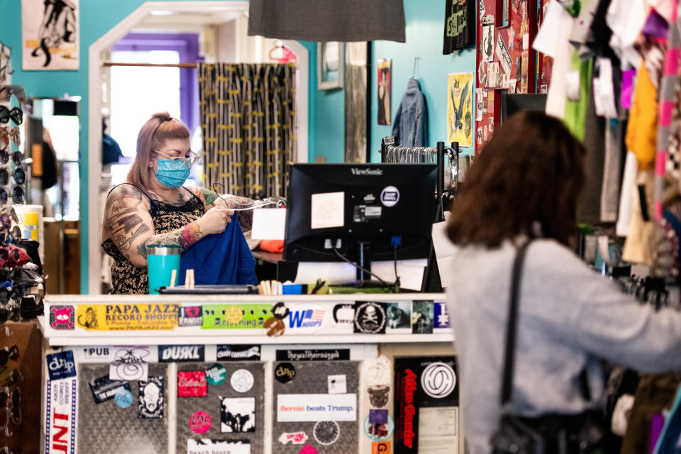 A worker wears a face mask at Sid and Nancy thrift and consignment store in Columbia, South Carolina, as a shopper browses a rack of clothes on April 23, 2020. (Photo: Sean Rayford via Getty Images)