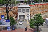 Small row house surrounded by giant hole in ground