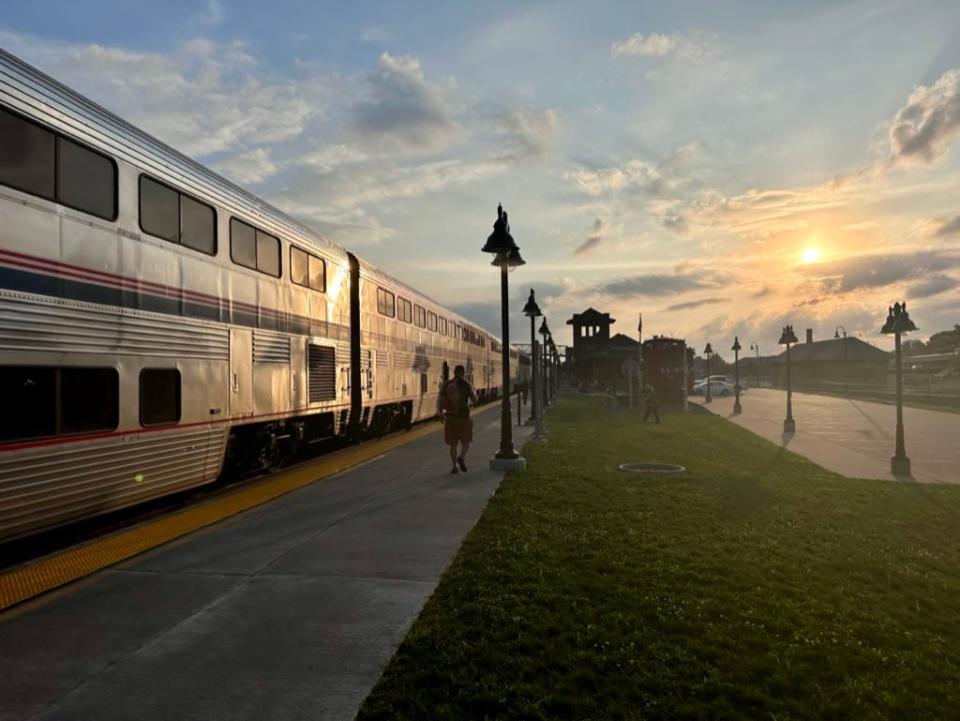An Amtrak train stopped at a station at sunset.