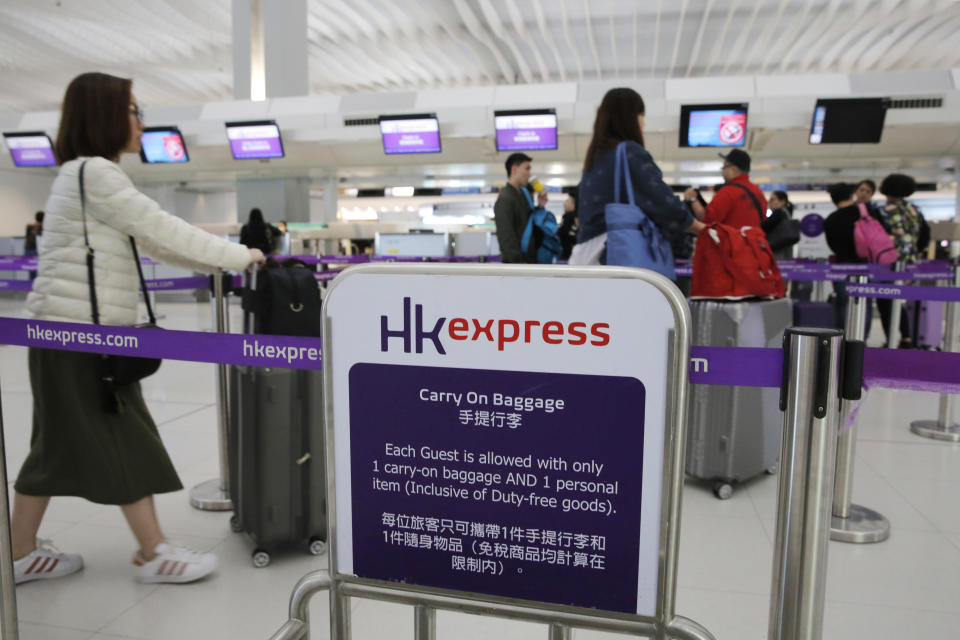 In this March 26, 2019 photo, passengers wait at the check-in counter of Hong Kong Express Airways at the Hong Kong International Airport. Cathay Pacific Airways is acquiring Hong Kong-based budget airline HK Express. Cathay said Wednesday, March 27, 2019, it will pay 4.93 billion Hong Kong dollars ($628 million) for HK Express. It said the acquisition will retain its identity as a separate brand and be operated as a low-cost carrier. (AP Photo/Kin Cheung)