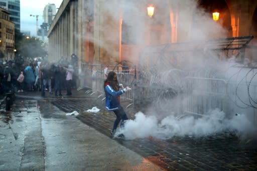 A Lebanese anti-government protester kicks back a tear gas canister fired by riot police from behind a barricaded road that leads to parliament in central Beirut on Sunday