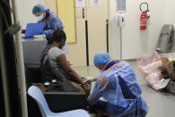 In this photo taken Thursday, March 26, 2020, Vincent Jactel, a member of the Civil Protection service, checks the pulse of a 27-year-old pregnant woman suspected of being infected with the Covid-19 virus in a social housing building in Paris. They don't have to put themselves in harm's way, but the volunteers of France's well-known Civil Protection service choose the front line in the fight against the coronavirus. They are often the first to knock on the doors of people calling for help, and who may have the infection or whose confirmed case has taken a downturn. (AP Photo/Michel Euler)