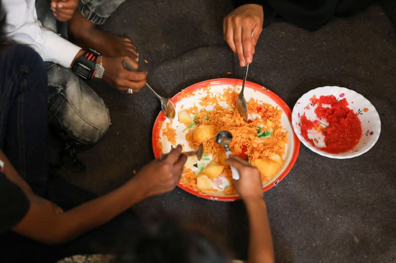 Amal Hasan and her children eat lunch at their hut in Sanaa