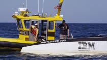 Sea Tow captain Ethan Maass, left, hooks the bow line of the Mayflower Autonomous Ship as Brett Phaneuf, co-director of the Mayflower Autonomous Ship project, looks on, Thursday, June 30, 2022, off the coast of Plymouth, Mass., after a crew-less journey from Plymouth, England. (AP Photo/Charles Krupa)