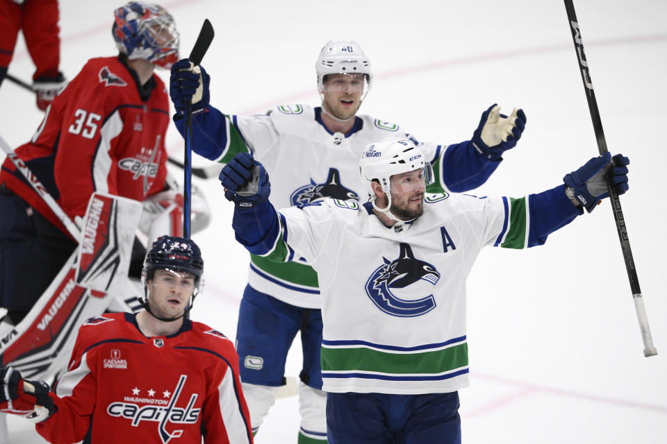 Vancouver Canucks center J.T. Miller, front right, celebrates after his winning goal during overtime of an NHL hockey game as Washington Capitals goaltender Darcy Kuemper (35) and center Connor McMichael (24) look on Sunday, Feb. 11, 2024, in Washington. Canucks center Elias Pettersson, top right, looks on. (AP Photo/Nick Wass)