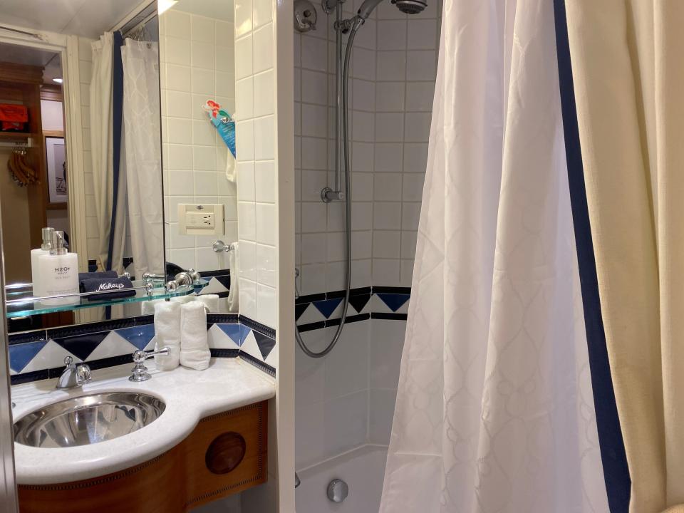 a bathroom with a sinch and a tub shower on a disney magic cruise ship