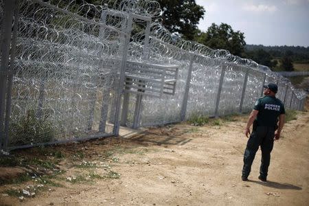 A Bulgarian border policeman stands in front of a barbed wire fence on the Bulgarian-Turkish border July 17, 2014. REUTERS/Stoyan Nenov