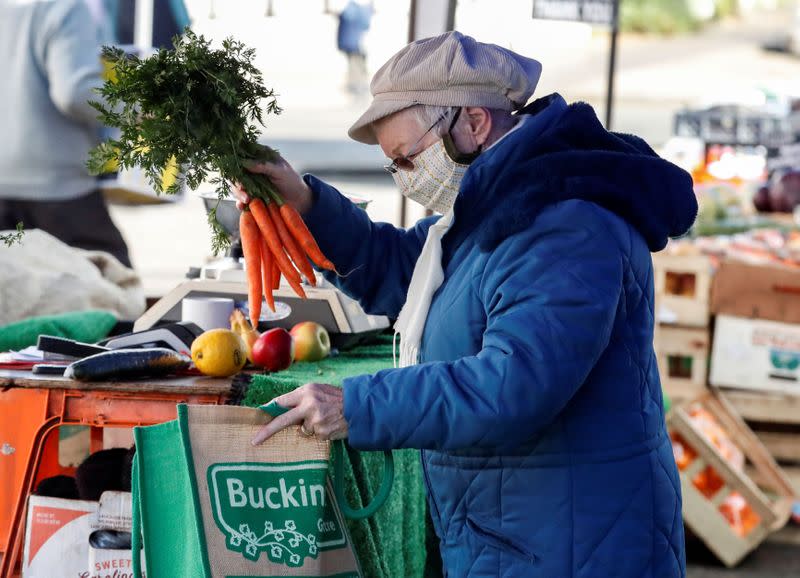 A lady buys carrots from a market stall in Buckingham, Britain