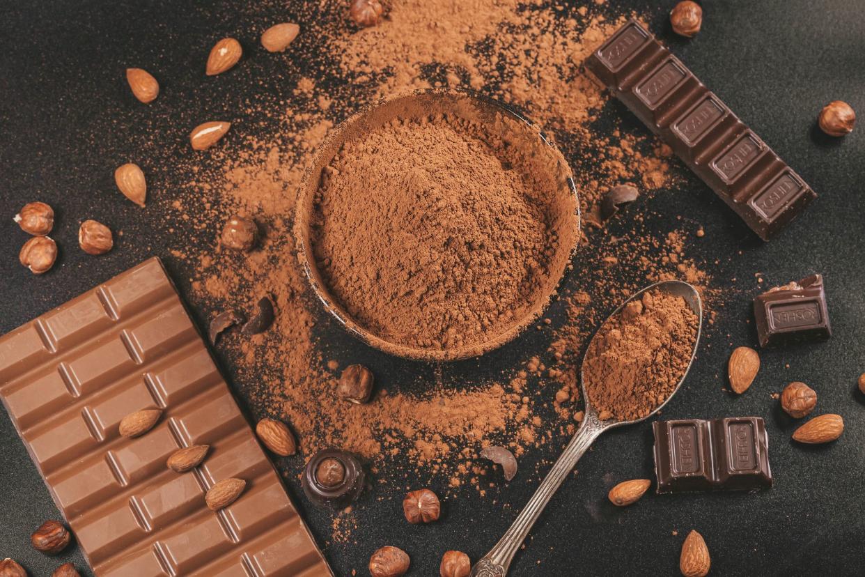 Milk and dark chocolate on a black background with nuts and cocoa, top view.