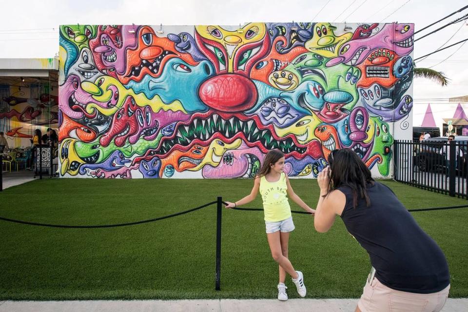 A visitor snaps a photo at the Kenny Scharf mural at the Wynwood Walls entrance.