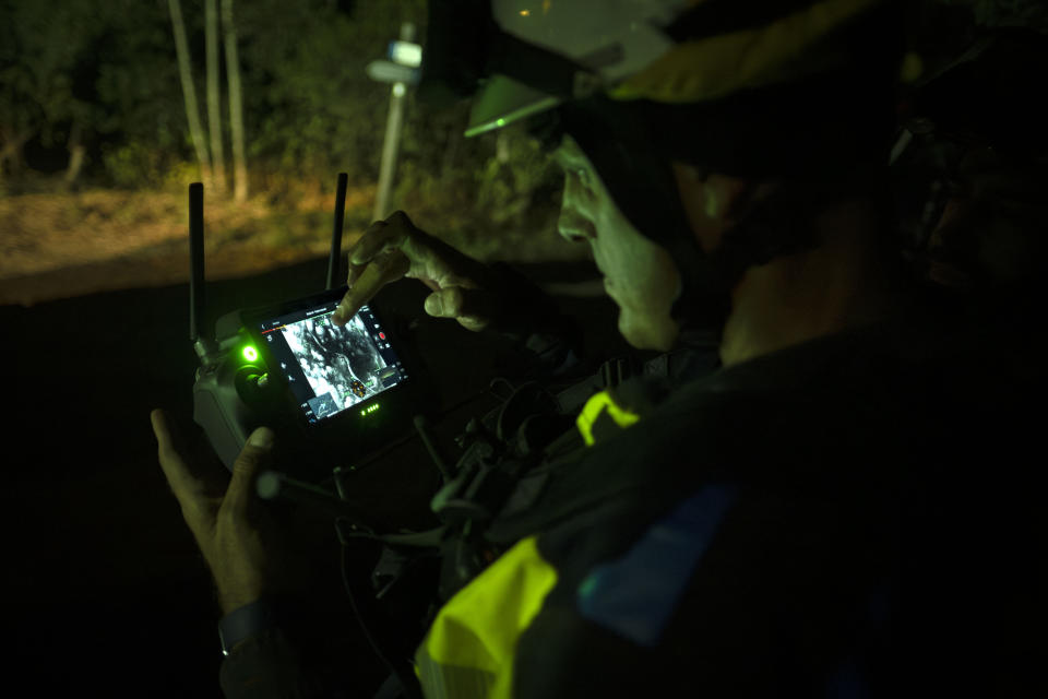 A firefighter uses a drone near the fire advancing through the forest toward the town of El Rosario in Tenerife, Canary Islands, Spain on Friday, Aug. 18, 2023. Officials say a wildfire is burning out of control through the Spanish Canary Island of Tenerife, affecting nearly 8,000 people who have been evacuated or ordered to stay indoors. (AP Photo/Arturo Rodriguez)