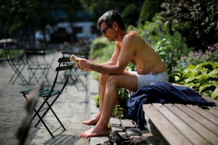 A man reads a book as he sunbathes on a hot summer day in Bryant Park in Manhattan, New York, U.S., July 1, 2018. REUTERS/Eduardo Munoz