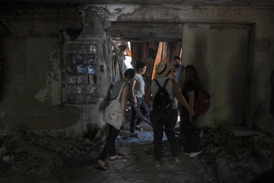 A group of Israelis on an educational tour visit a house that was torched by Hamas militants on the Oct. 7 attack on Israel in Kibbutz Nir Oz, on Friday, June 21, 2024. A new kind of tourism has emerged in Israel in the months since Hamas’ Oct. 7 attack. For celebrities, politicians, influencers and others, no trip is complete without a somber visit to the devastated south that absorbed the brunt of the assault near the border with Gaza. (AP Photo/Ohad Zwigenberg)