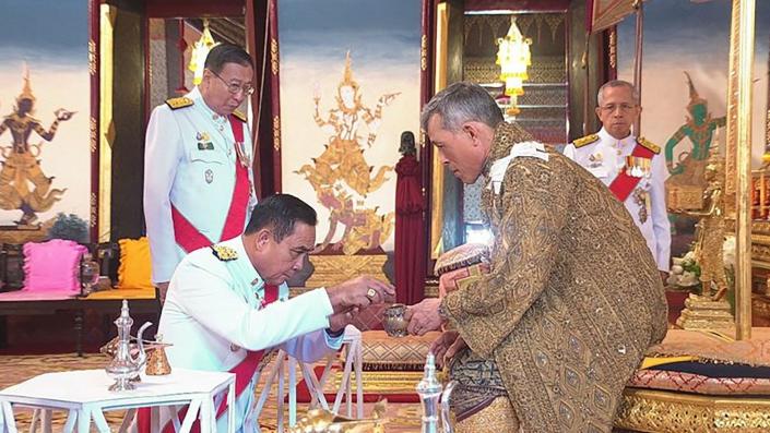 Thai Prime Minister Prayuth Chan-ocha, left, bows before King Vajiralongkorn.