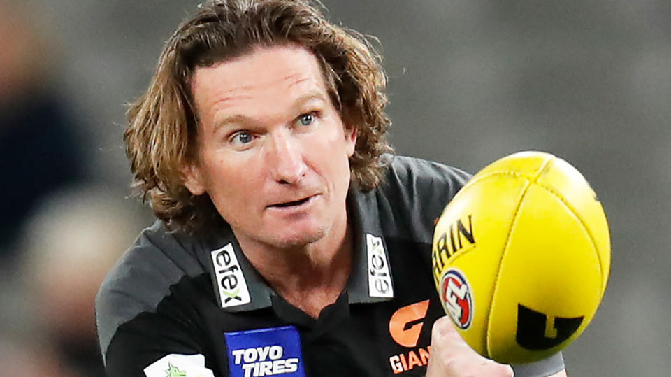 James Hird handballs to a player while assistant coach for the GWS Giants.