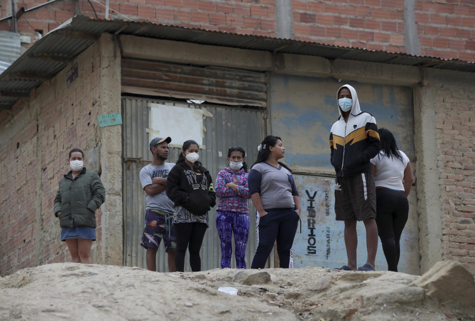 La gente espera afuera de sus hogares para recibir alimentos donados en las afueras de Bogotá, Colombia, el lunes 30 de marzo de 2020, en medio de una cuarentena para ayudar a contener la propagación del nuevo coronavirus. (AP Foto / Fernando Vergara)