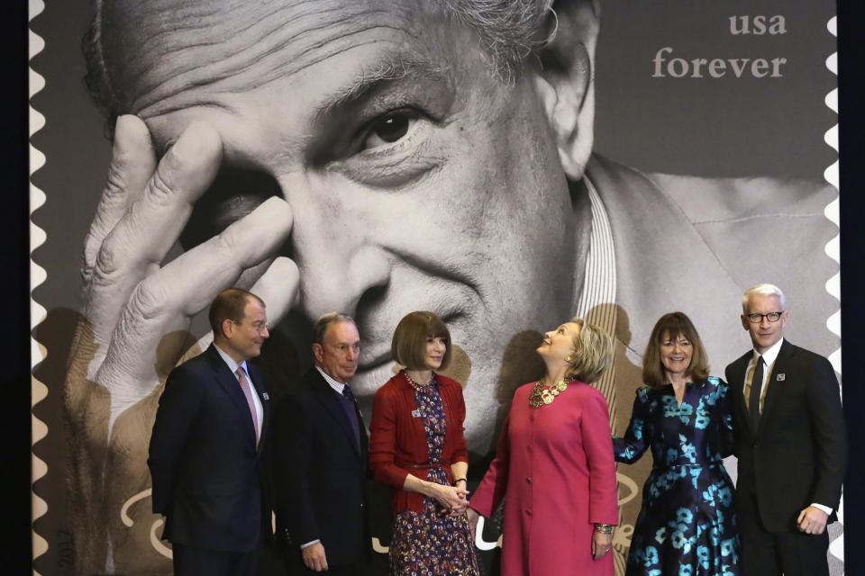 Hillary Clinton, third from right, looks at one of the Oscar de la Renta stamps unveiled during ceremonies in Grand Central Terminal, in New York, Thursday, Feb. 16, 2017. Also in attendance is, from left, Oscar de la Renta CEO Alexander Bolen, Michael Bloomberg, Vogue Editor Anna Wintour, Clinton, U.S. Postal Service Vice President Janice Walker and journalist Anderson Cooper. Clinton has praised Oscar de la Renta as an inspiration to striving immigrants like himself at an event honoring the late fashion designer with a series of commemorative stamps. (AP Photo/Richard Drew)