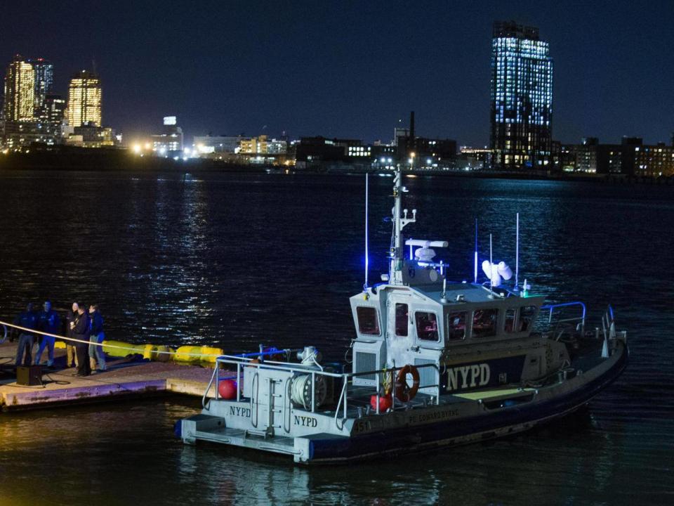 Yellow buoys that a New York police officer said are suspending the helicopter that crashed on the East River float next to a NYPD police boat. (AP Photo/Andres Kudacki)