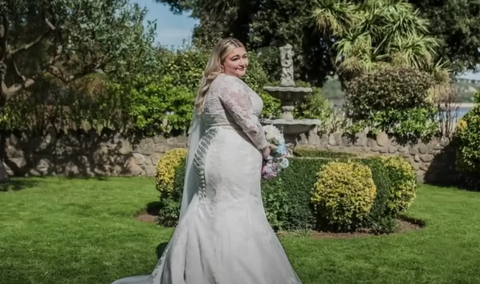 Kayley Stead poses in a garden in her wedding dress. 