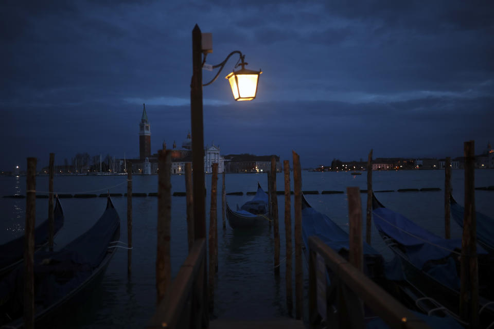 Boats sail along the lagoon next to parked gondolas in Venice, Italy, Tuesday, March 3, 2020. Venice in the time of coronavirus is a shell of itself, with empty piazzas, shuttered basilicas and gondoliers idling their days away. A UNESCO world heritage site, it had already been brought to its knees last year, when near-record high tides flooded a lagoon city used to frequent spells of "aqua alta." (AP Photo/Francisco Seco)